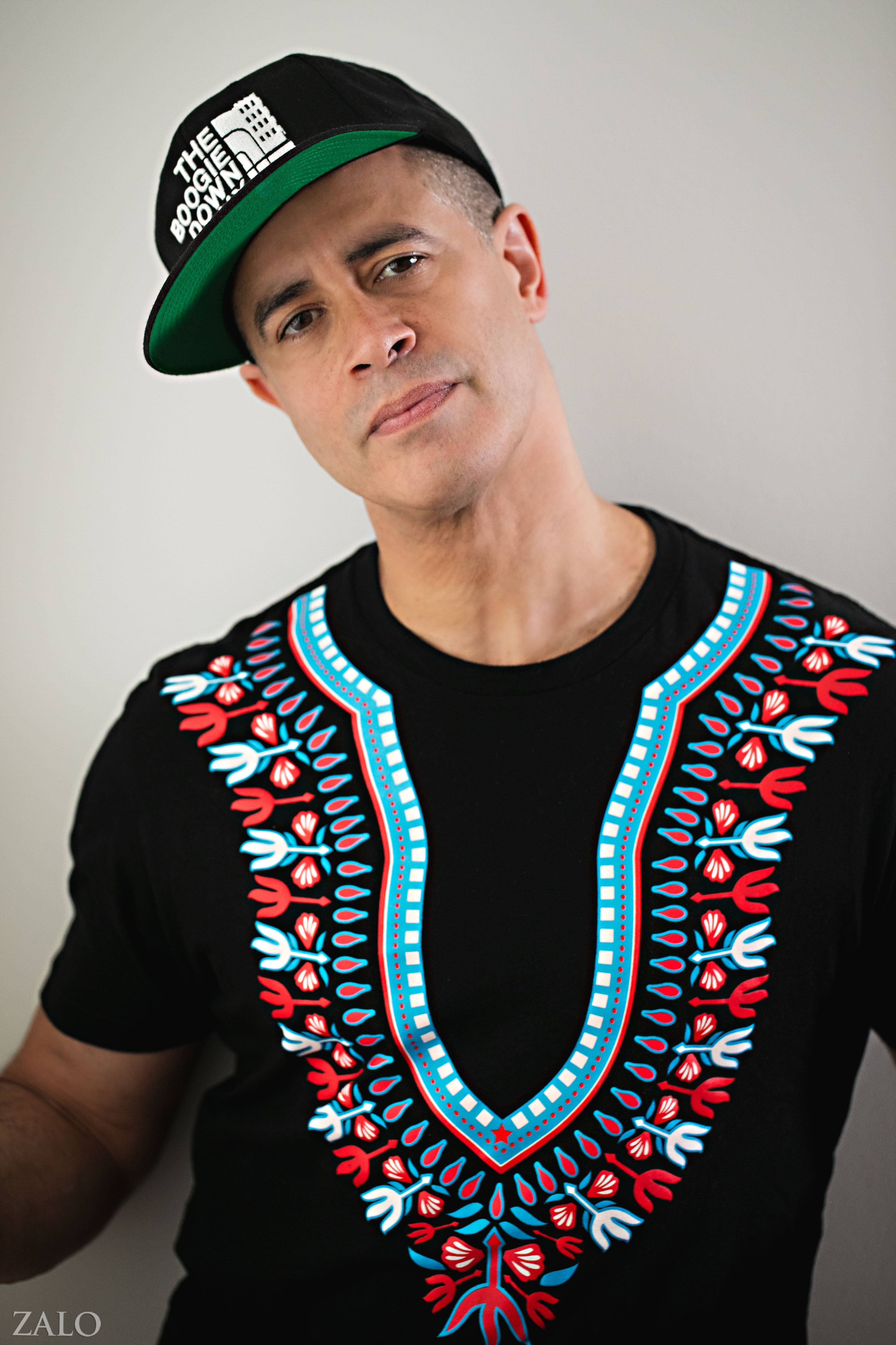 Portrait of Richard “Crazy Legs” Colón in a black cap and dashiki-print shirt