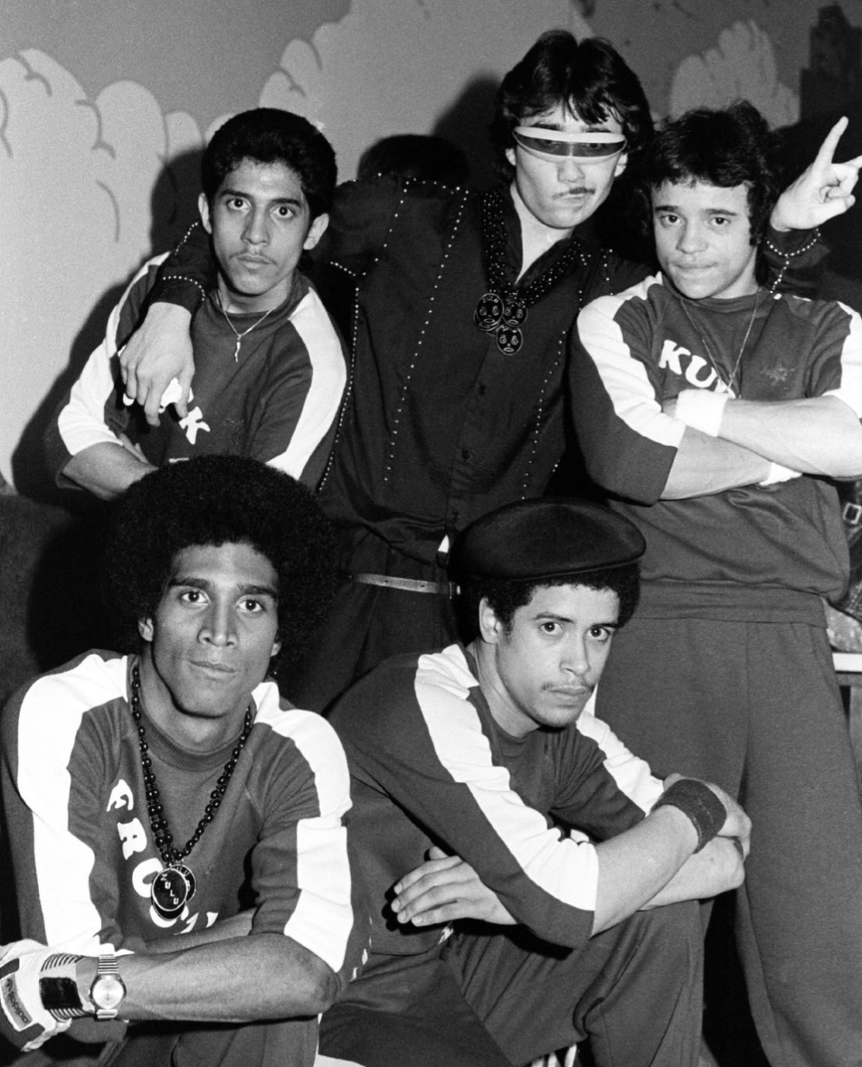 Black-and-white studio portrait of five Rock Steady Crew members in matching crew shirts