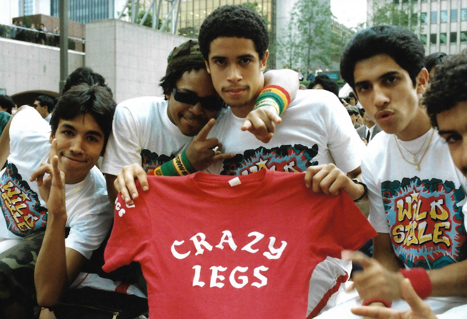 Rock Steady Crew members in Wild Style t-shirts hold up a red Crazy Legs shirt in a Tokyo plaza
